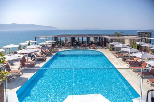 a swimming pool with chairs and umbrellas and the ocean at Hotel Vlora Priam, Affiliated by Melia in Vlorë