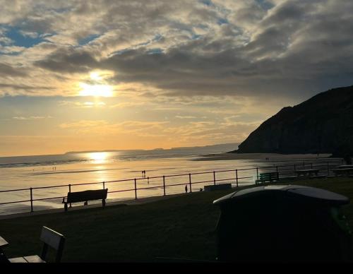 a sunset over a beach with a bench and the ocean at Vern's Van in Pendine