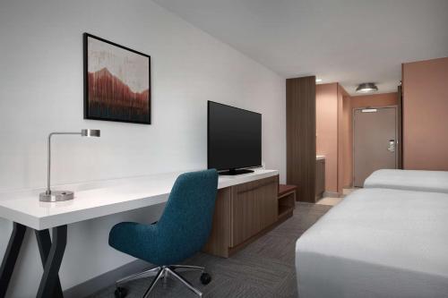 a hotel room with a desk with a bed and a tv at Hilton Garden Inn Denver Airport Tower Road in Denver