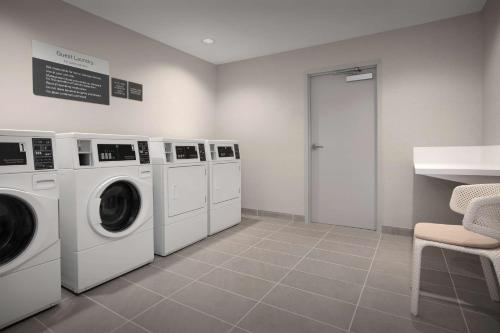 a laundry room with three washing machines and a counter at Hilton Garden Inn Denver Airport Tower Road in Denver