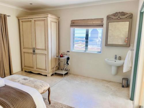 a bathroom with a bed and a sink and a window at Bamboesbaai Beach House in Jacobs Bay