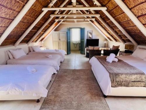 a attic room with four beds and a desk at Bamboesbaai Beach House in Jacobs Bay
