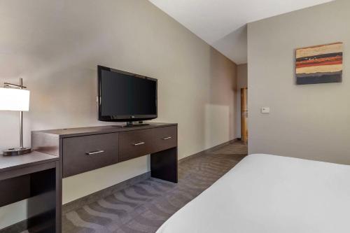 a hotel room with a bed and a flat screen tv at Comfort Suites Boise West Meridian in Meridian