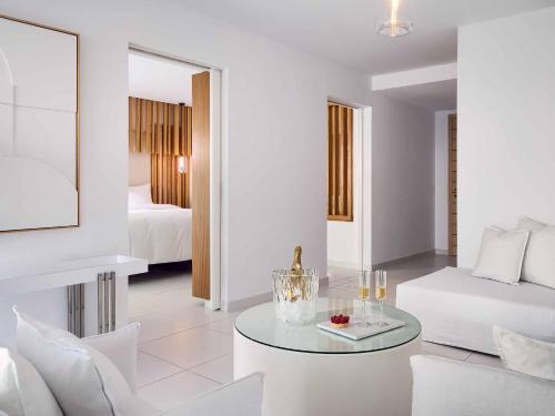 a white living room with a couch and a table at Grecotel LUXME White in Adelianos Kampos