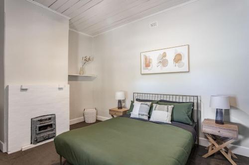 a bedroom with a green bed and a fireplace at Maranka Homestead in Waikerie