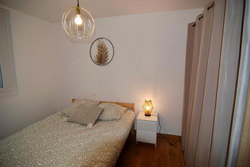 - une petite chambre avec un lit et une lampe dans l'établissement Bel appartement de quartier, terrasse et jardin, à Montélimar