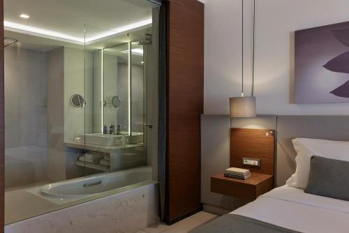 - une chambre avec une salle de bains pourvue d'un lavabo et d'un lit dans l'établissement Atlantica Kalliston Resort - Adults Only, à Stalós
