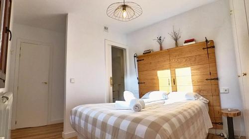 a bedroom with a large bed with a wooden headboard at Hadar Deluxe - tucasaenlospirineos in Escarrilla
