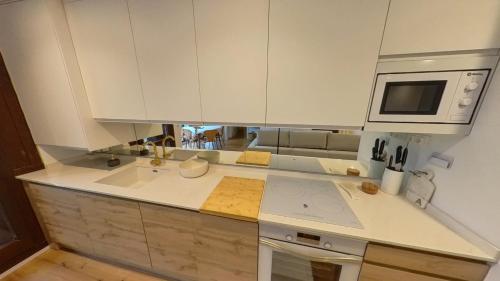 a kitchen with white cabinets and a sink and a microwave at Hadar Deluxe - tucasaenlospirineos in Escarrilla