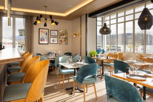 restauracja ze stołami, krzesłami i oknami w obiekcie Le Bel Abri w Annecy