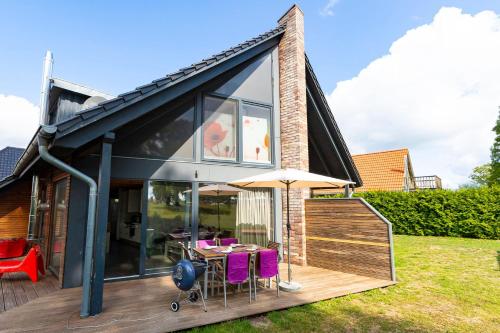 a house with a table and chairs on a deck at Ferien_HAUS AM AHORNECK _ THEA in Göhren-Lebbin