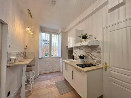 une cuisine avec des placards blancs, une fenêtre et une porte dans l'établissement Studio cosy au centre-ville aux calmes, à Avignon