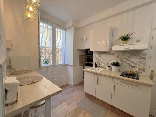 une cuisine avec des armoires blanches et un comptoir dans l'établissement Studio cosy au centre-ville aux calmes, à Avignon