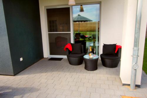 a patio with two chairs and a table with a glass door at Ferienhaus CASA OASIS in Göhren-Lebbin