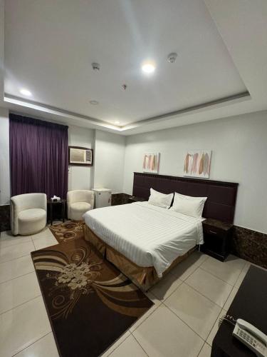 a bedroom with a bed and two chairs in it at Al Thanaa Alraqi Furnished Apartments in Jeddah