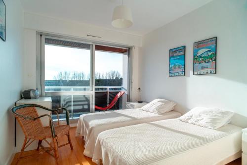 deux lits dans une chambre avec une fenêtre dans l'établissement Ty Cartier - A 200 m de la plage, à Bénodet