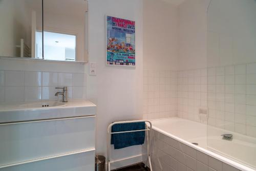 une salle de bain blanche avec une baignoire et un lavabo dans l'établissement Ty Cartier - A 200 m de la plage, à Bénodet