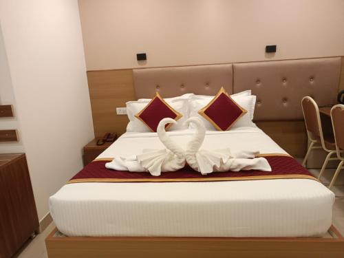 two white swans sitting on top of a bed at Hotel Hebron Suites in Bengaluru