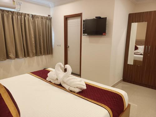 a room with a bed with a towel animal on it at Hotel Hebron Suites in Bengaluru