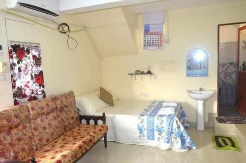 a room with a couch and a bed and a sink at Manimalar guest in Colombo