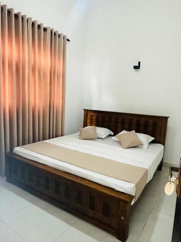 a bed sitting in a room with a curtain at Zuulas Palace in Dickwella