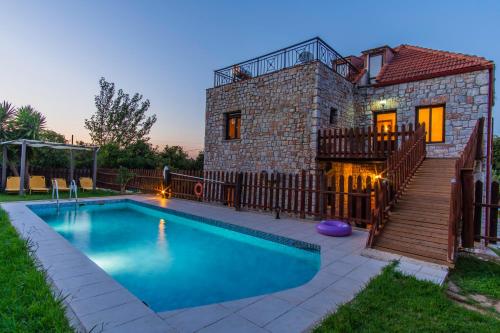 a villa with a swimming pool in front of a house at Villa Kamaraki in Patellárion