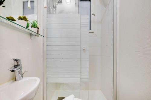 une salle de bain blanche avec une douche et un lavabo dans l'établissement Magnificent apartment - 1BR 4P - Sacré-Cœur, à Paris