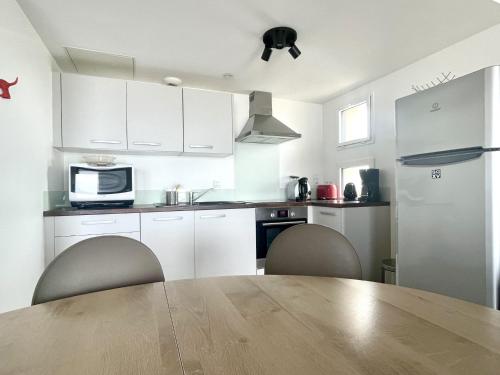 une cuisine avec des placards blancs et une table en bois avec des chaises dans l'établissement Le Banc de Sable, à Saint-Gilles-Croix-de-Vie