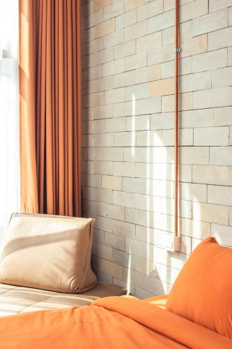 a bed with an orange pillow and a brick wall at Takak Villas in Siem Reap