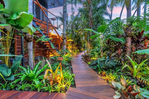 a wooden pathway through a tropical garden with palm trees at The Palms At Palm Cove in Palm Cove