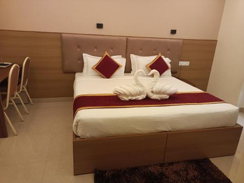 a bedroom with a bed with two swans on it at Hotel Hebron Suites in Bengaluru