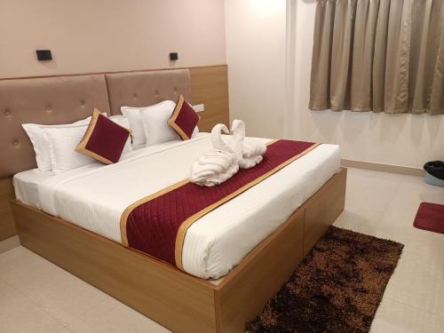 a bedroom with a bed with a stuffed animal on it at Hotel Hebron Suites in Bengaluru