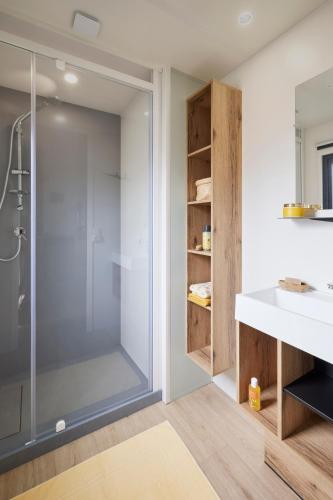 une salle de bain avec une douche en verre et un lavabo dans l'établissement Camping du Lac de Pouzauges à 15' du PuyduFou, à Pouzauges