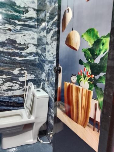 a bathroom with a toilet and a painting of the ocean at Kathoo's Lakeview Homestay in Alleppey