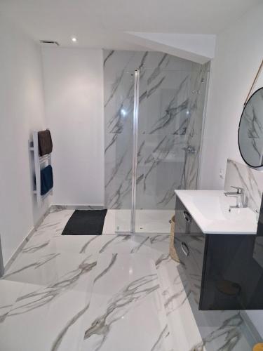 La salle de bains est pourvue d'une douche en marbre et d'un lavabo. dans l'établissement village house, à Villegly
