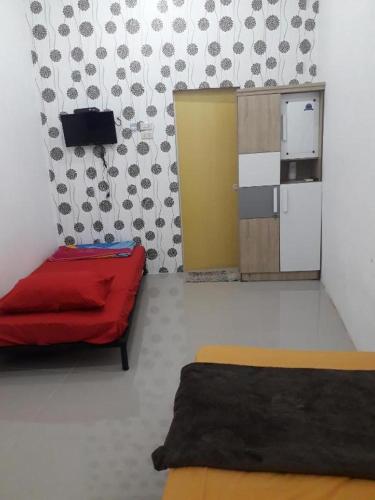 a room with a red bed and a refrigerator at Ahza syariah in Rantauprapat