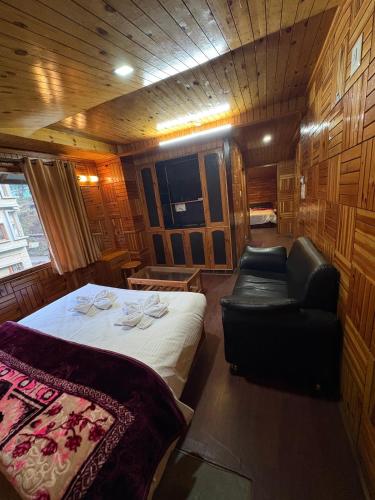 a bedroom with a bed and a couch and a chair at Aurave Inn in Kasol