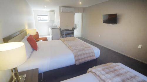 a hotel room with two beds and a television at Abbey Motor Lodge in Christchurch