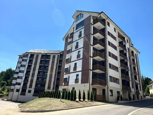 a tall apartment building with trees in front of it at Tanasković Home Zlatibor in Zlatibor