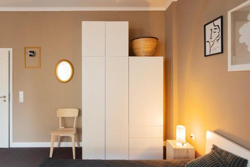 a bedroom with a white cabinet and a chair at Huge apartment with Sauna and free parking in Duisburg