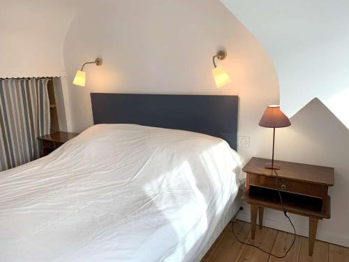 - une chambre avec un lit blanc et une table de chevet avec une lampe dans l'établissement Maison de charme à 400m de la plage de Trestraou à PERROS-GUIREC - Réf 506, à Perros-Guirec