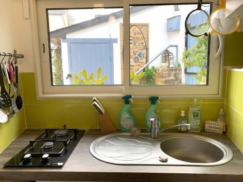 un comptoir de cuisine avec un évier et une fenêtre dans l'établissement Maison de charme à 400m de la plage de Trestraou à PERROS-GUIREC - Réf 506, à Perros-Guirec