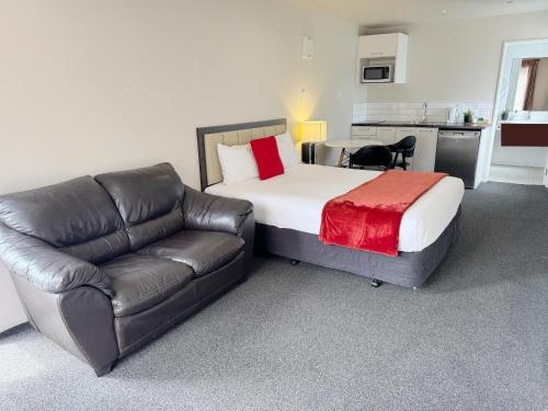 a bedroom with a bed and a leather couch at Abbey Motor Lodge in Christchurch