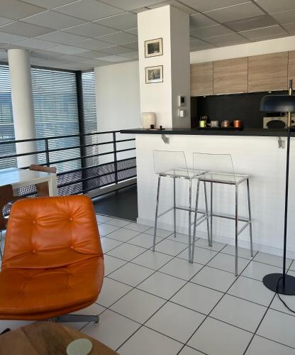 une cuisine avec une chaise orange et un comptoir dans l'établissement Un duplex à PARIS DAUMESNIL, à Paris