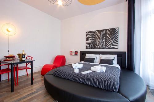 - une chambre avec un grand lit noir et une chaise rouge dans l'établissement L'Hyper Centre - Netflix & Wifi - Literie Haut de Gamme - check-in 24H24 - GoodMarning, à Châlons-en-Champagne