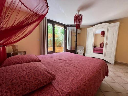 a bedroom with a large bed with a red blanket at La Petite Chapelle in Velleron