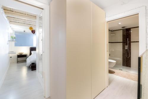 a white bathroom with a glass door leading to a bedroom at Riccardo Luxury Apartment in Bari