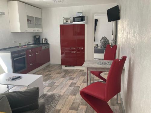 a small kitchen with a table and red chairs at Müritz Apartments in Waren