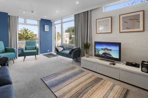 a living room with a flat screen tv and blue chairs at Heathcliff, Coastal Walks and Sea Views in Brixham
