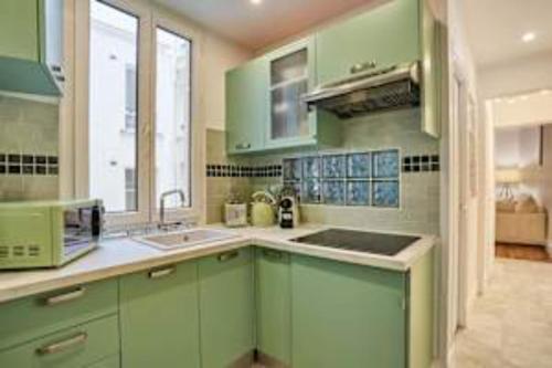 d'une cuisine avec des placards verts, un évier et une fenêtre. dans l'établissement Superb Apartment Le Marais Place des Vosges, à Paris